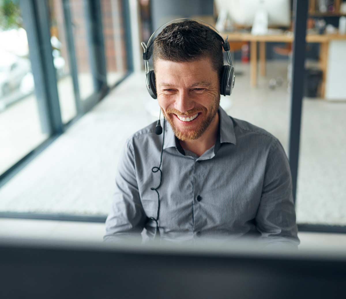 Man som sitter framför datorskärm och ler